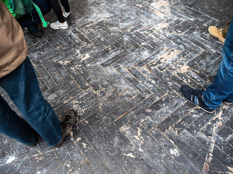 Multiple people feets on the old wooden parquet floor