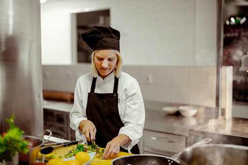 Young chef woman prepare food in professional kitchen