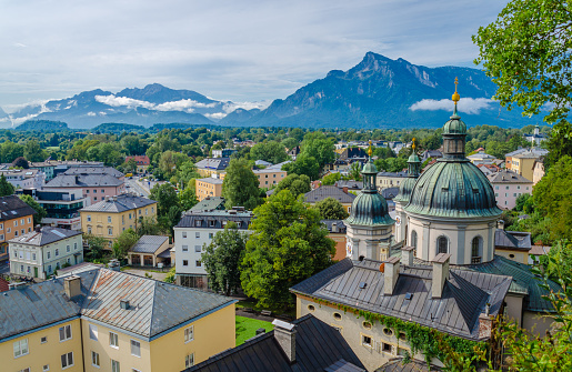 Blick auf das Nonntal in Salzburg mit der Kirche St. Erhard an einem Sommertag, im Hintergrund Bergpanorama der Alpen