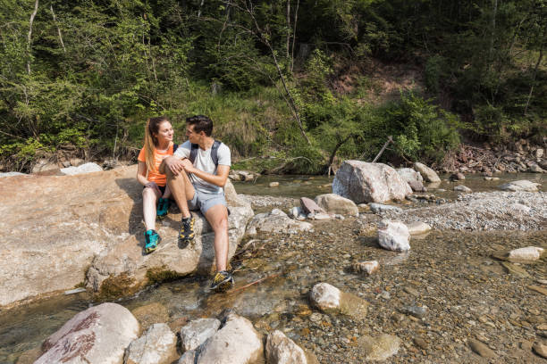 istock Couple taking a break from hiking, sitting on the river bank 2038672437