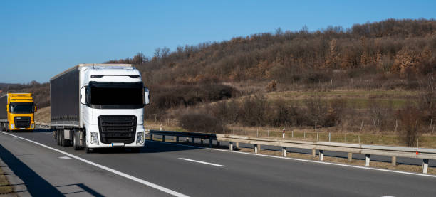 istock Two large trucks drive on the highway one behind the other. 2038674026