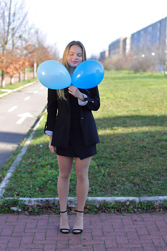 Joyful teenager girl with balloons outside on the street