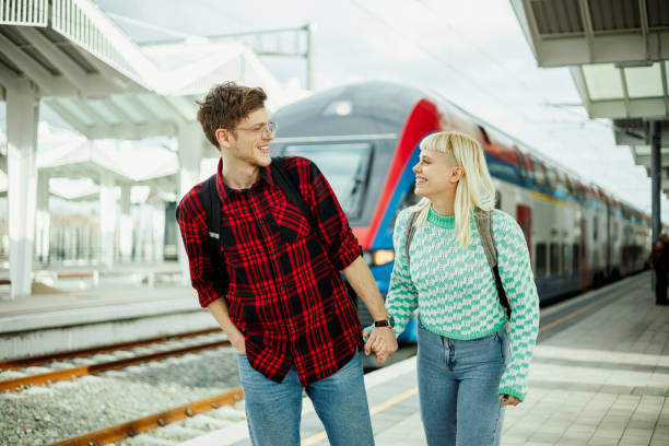istock Couple holding hands at the train station while waiting for a train to arrive 2038743135