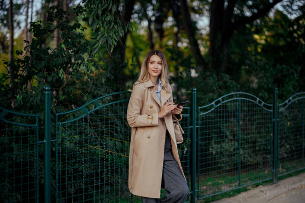 istock A young woman on a street using her phone next to a park area. 2038771668