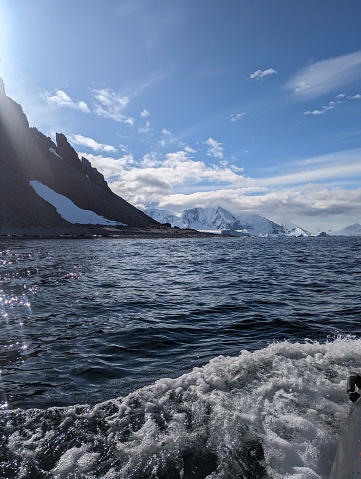 Waves with mountains and glaciers in the background in Antartica waters