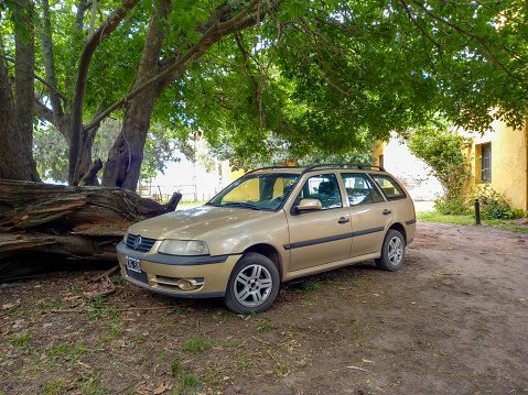 Chascomús, Argentina - Nov 18, 2023: Classic car beige 1990s Volkswagen Gol Country Wagon under a tree in a garden. Copy space