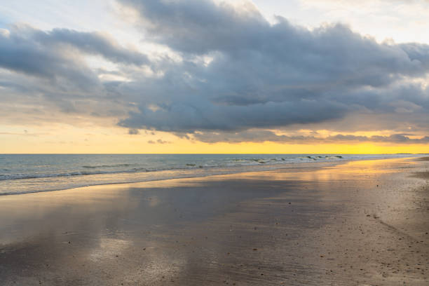 Sunset paints the sky with warm hues over a tranquil beach.