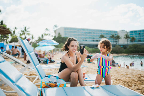 istock Woman talks on phone while sitting with daughter on the beach 2038951367