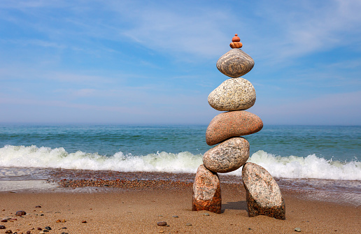 Stone zen pyramid made of colorful pebbles on the beach against a stormy sea. Concept of Life balance, harmony and meditation