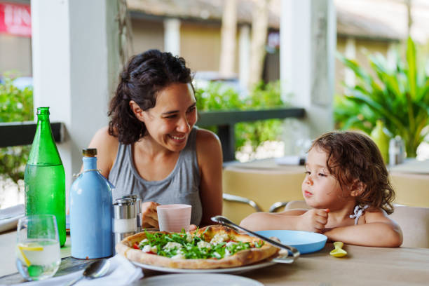 Mother and toddler daughter talk while enjoying lunch outside