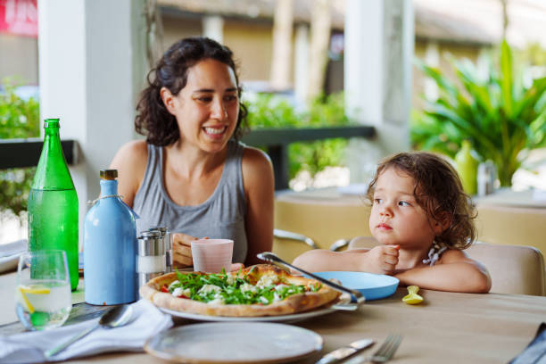 istock Smiling mother sits at restaurant table with daughter 2038985755