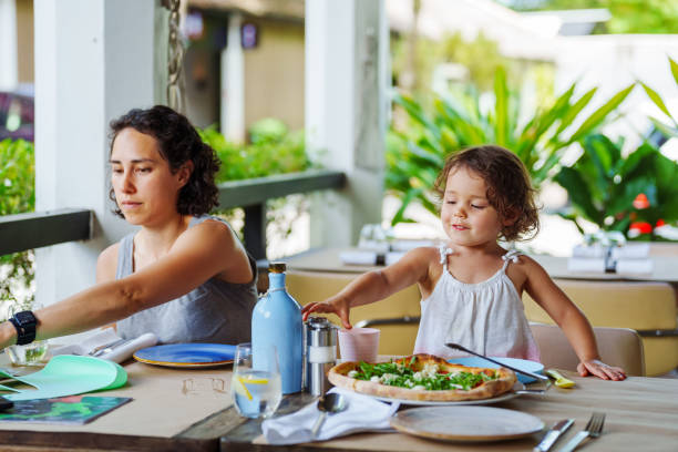 istock Mother eats lunch with toddler daughter outside at restaurant table 2038985764