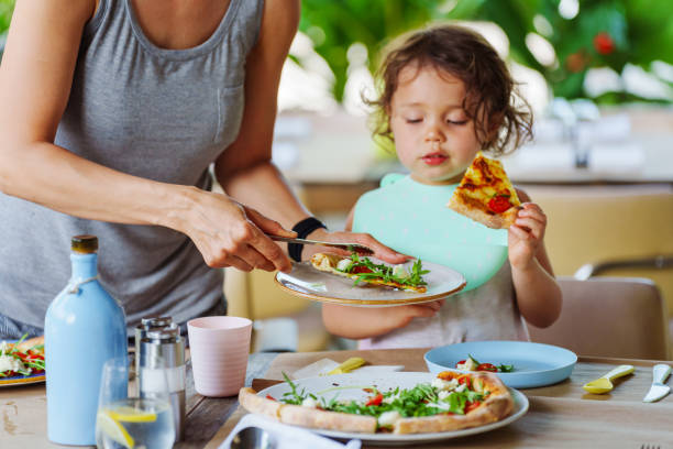 istock Young girl eats pizza with mother while at outdoor restaurant 2038985768