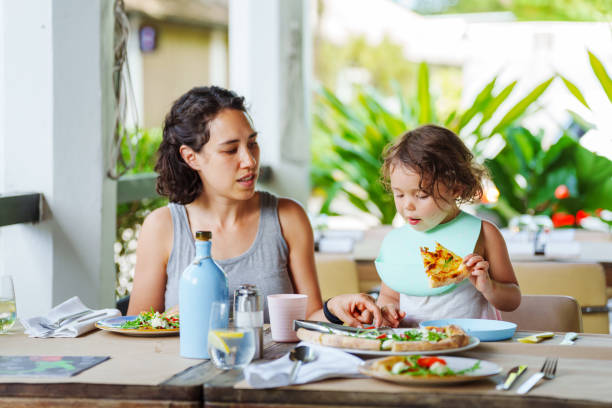 istock Young girl eats pizza with mother while at outdoor restaurant 2038985778