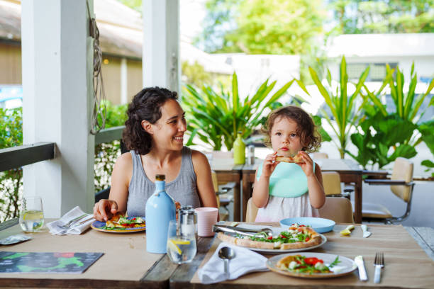 Smiling mother sits at restaurant table with daughter