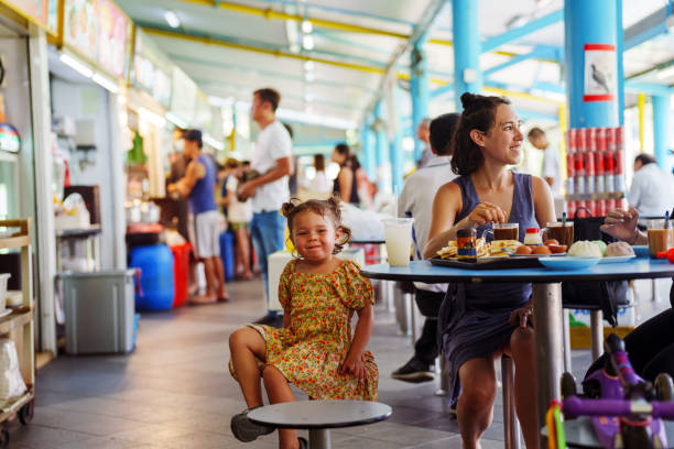 Young girl smiles while sitting with mother in a cafeteria