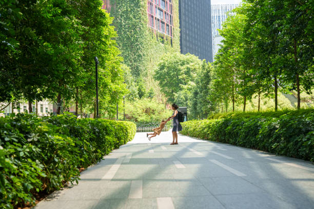 Mother twirls toddler daughter around while on a walking path