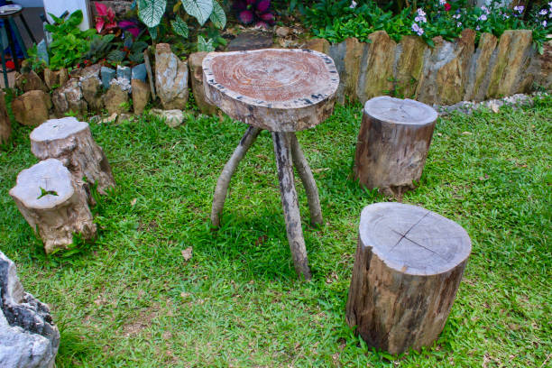 Table and chairs made of logs in the garden on green grass.
