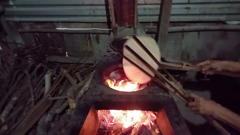 Hands baking rice paper on a traditional fire stove in Mekong Delta Vietnam.