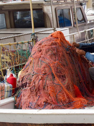Fisherman mending traditional fishing nets by hand on the boat