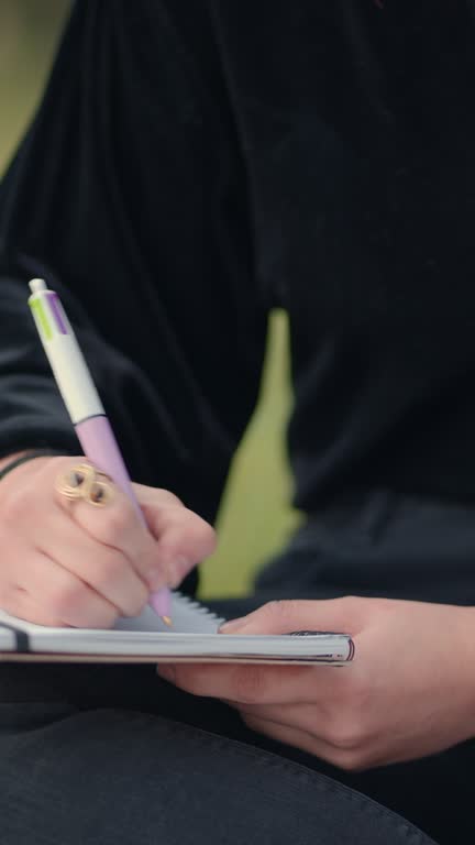 hand writing with a pen on notepad, close up view. Lower body, female