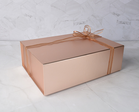 beautiful festive Christmas birthday premium luxury gift box packaging in shining bronze color and ribbon on white marble table different angle top view design photo shoot