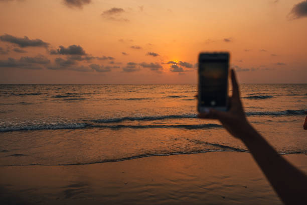 istock Sunset on the beach and mobile phone taking photos 2039304444