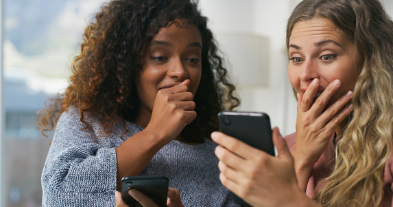 Shock, phone and girl friends scroll on social media, mobile app or the internet in living room. Surprise, technology and young women with a wtf, omg or wow face expression for browsing on cellphone.