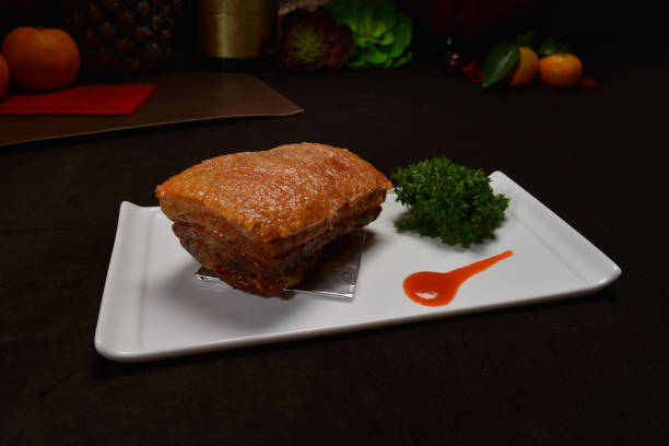 famous crispy roasted bbq pork belly meat cut slices in long plate on black background Hong Kong banquet food appetiser menu for restaurant