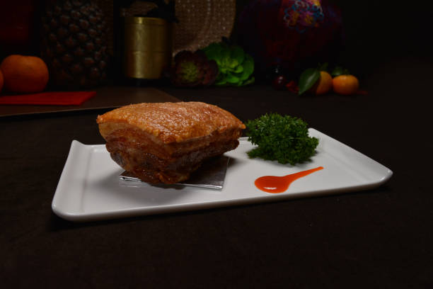 famous crispy roasted bbq pork belly meat cut slices in long plate on black background Hong Kong banquet food appetiser menu for restaurant