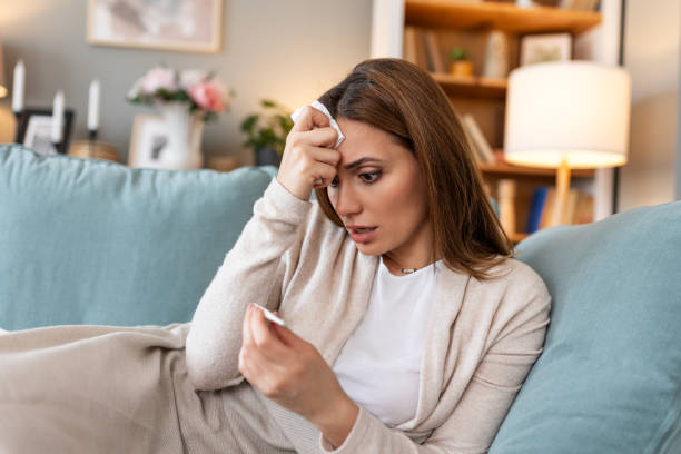 istock Sickness, seasonal virus problem concept. Woman being sick having flu lying on sofa looking at temperature on thermometer. Sick woman lying in bed with high fever. Cold flu and migraine. 2039411792