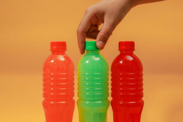 Selective focus, Bottles of multi colored juices on light orange background