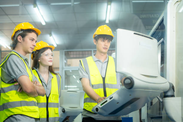 both of  young factory worker wearing a hard hat looking at a computer screen used to control production. - computer control room hardhat computer monitor 뉴스 사진 이미지