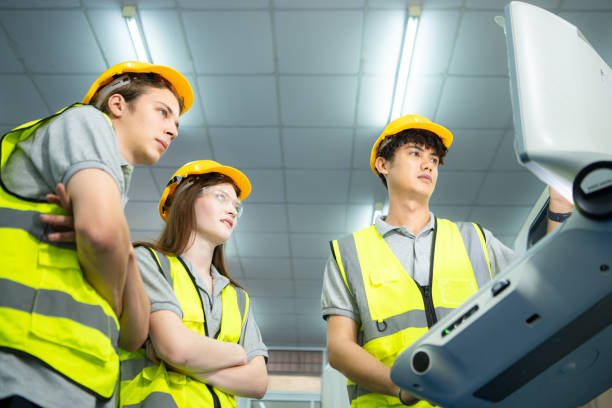 both of  young factory worker wearing a hard hat looking at a computer screen used to control production. - computer control room hardhat computer monitor 뉴스 사진 이미지