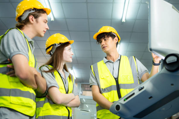 both of  young factory worker wearing a hard hat looking at a computer screen used to control production. - computer control room hardhat computer monitor 뉴스 사진 이미지