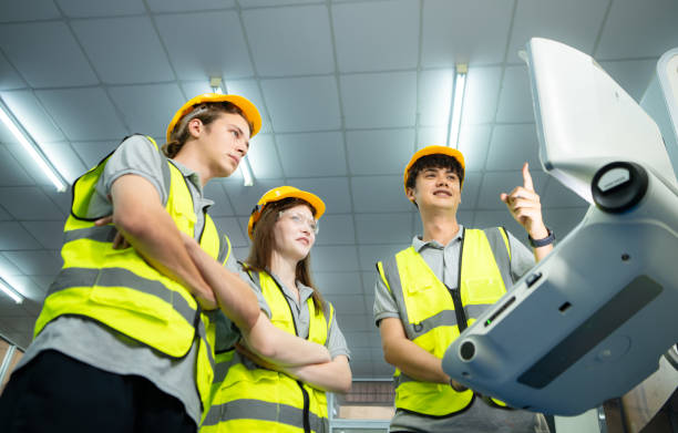 both of  young factory worker wearing a hard hat looking at a computer screen used to control production. - computer control room hardhat computer monitor 뉴스 사진 이미지