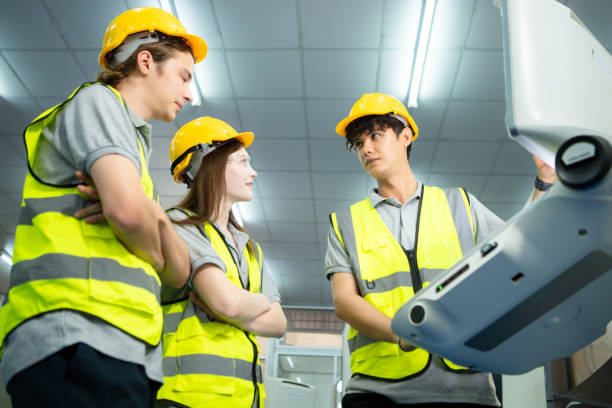 both of  young factory worker wearing a hard hat looking at a computer screen used to control production. - computer control room hardhat computer monitor 뉴스 사진 이미지