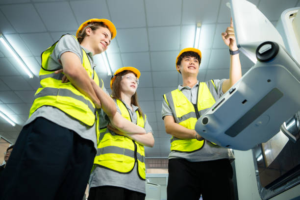 both of  young factory worker wearing a hard hat looking at a computer screen used to control production. - computer control room hardhat computer monitor 뉴스 사진 이미지