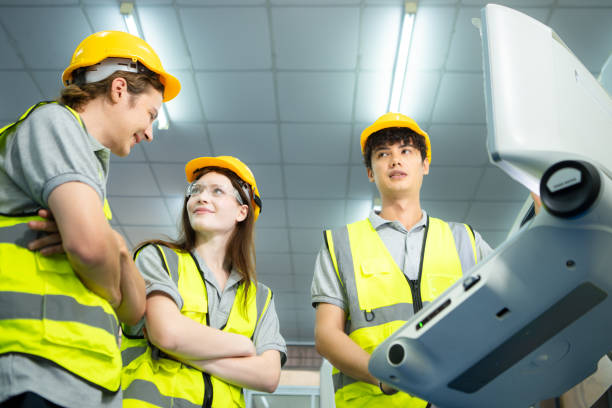 both of  young factory worker wearing a hard hat looking at a computer screen used to control production. - computer control room hardhat computer monitor 뉴스 사진 이미지