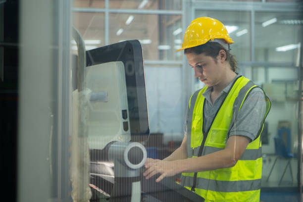 istock Young man factory worker wearing a hard hat looking at a computer screen used to control production. 2039430764