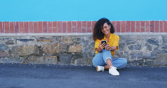 Smile, phone and woman on ground at wall in city on social media, internet and typing outdoor. Happy person on smartphone, street and reading email on mobile app, communication or mockup space online