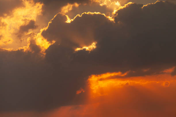 Beautiful vibrant orange sunrise sky with sun rays between clouds. High quality photo.