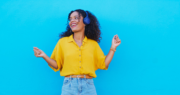 Music, dance and freedom with a black woman on blue background mockup for marketing or advertising. Smile, radio and headphones with a happy young person streaming audio or listening to a song