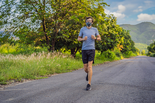 Runner wearing medical mask, Coronavirus pandemic Covid-19. Sport, Active life in quarantine surgical sterilizing face mask protection. Outdoor run on athletics track in Corona Outbreak.