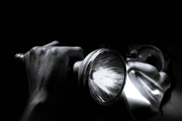 A clown figure holding a flashlight in the dark,