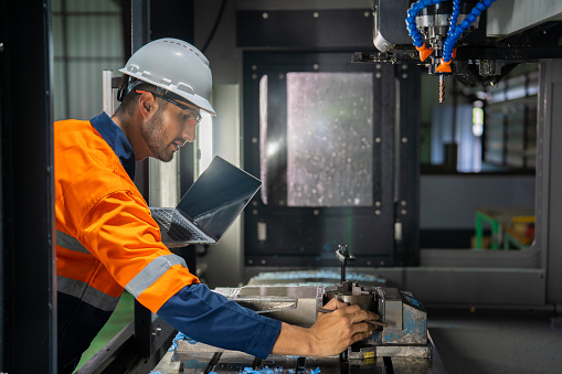 Experience the unfolding of engineering excellence in this captivating image featuring a Hispanic engineer setting up a CNC milling machine. The photograph encapsulates the meticulous attention to detail, showcasing the expertise required in the intricate process. A visual narrative of precision and dedication in the world of cutting-edge technology.
