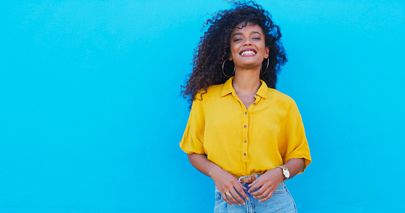 Happy, fun and portrait of a woman on a blue background with mockup for fashion information. Smile, young and a stylish girl or model with space on a wall in the city with an urban personality