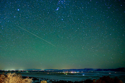 Saguache County, Colorado, USA - February 12, 2024: A night view of the San Luis Valley showing star trails and commercial airplanes flying through the night sky.