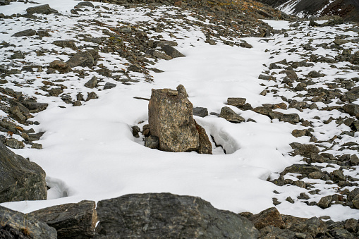 Rock in snowdrift in rocky valley.