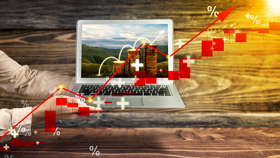 Business hand showing laptop screen with a view of stair stack of the golden coin with rising inflation graph arrow. Inflation concept